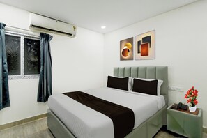 Una habitación de hotel con cama, mesita de noche, ventana con cortinas y decoración en la pared.
