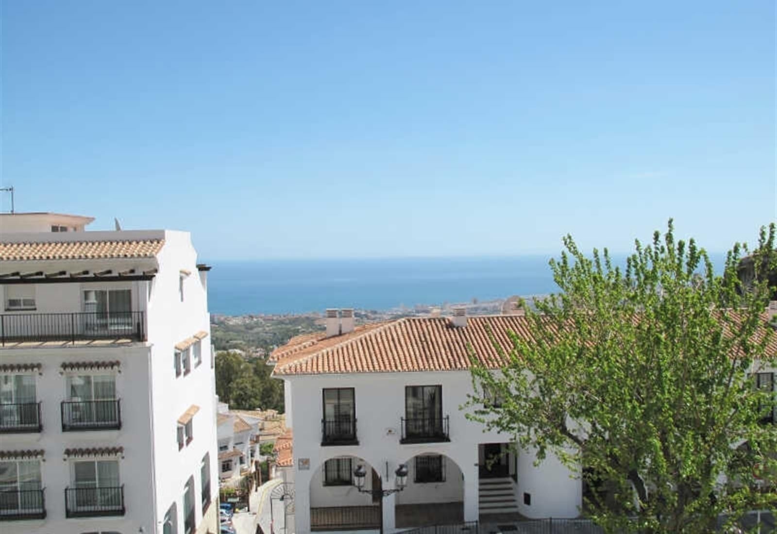 Vista costera con edificios, cielo despejado y el mar al fondo.