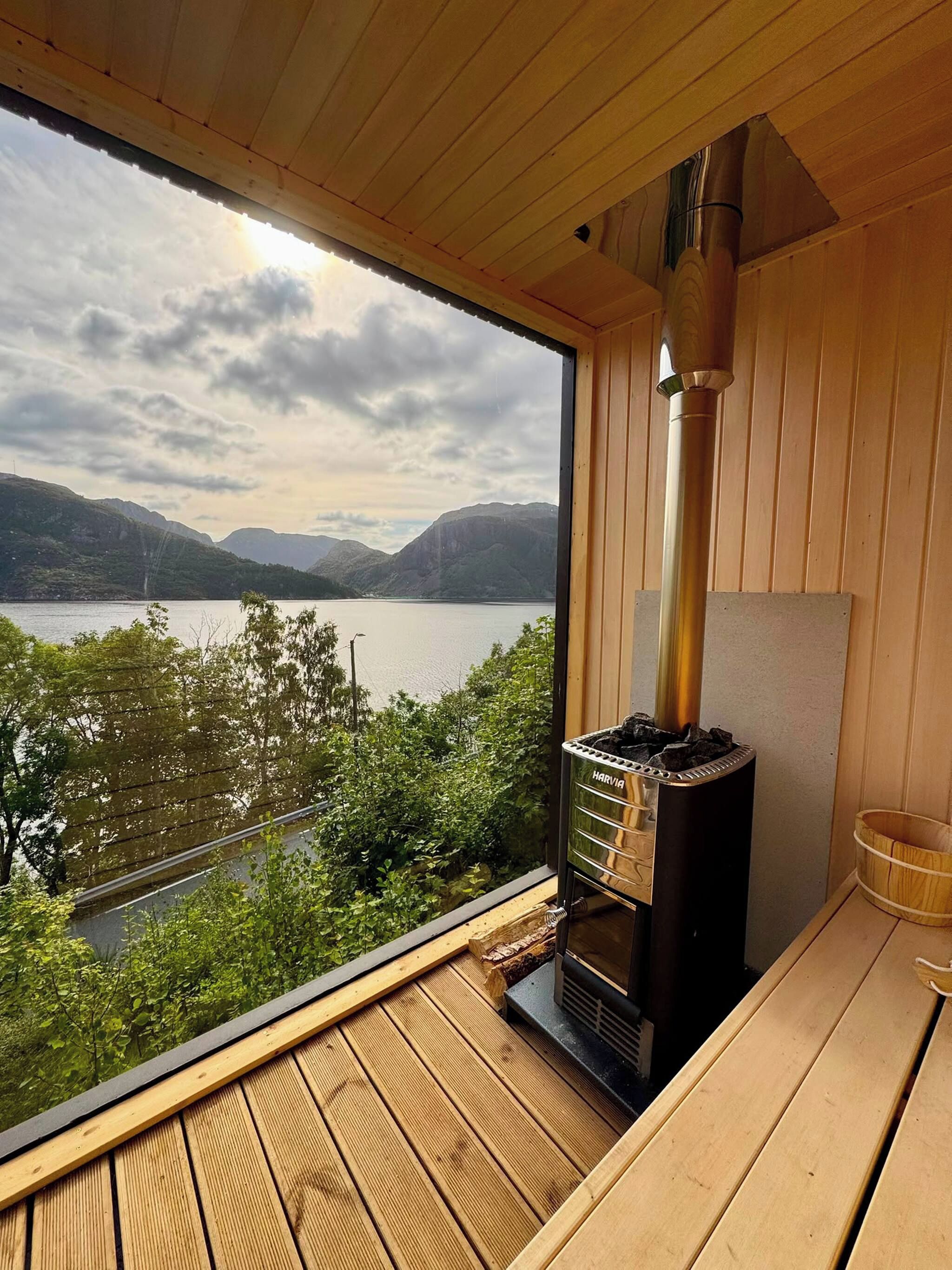 Une terrasse en bois offrant une vue sur un lac et des montagnes, un poêle à bois et un banc en bois.