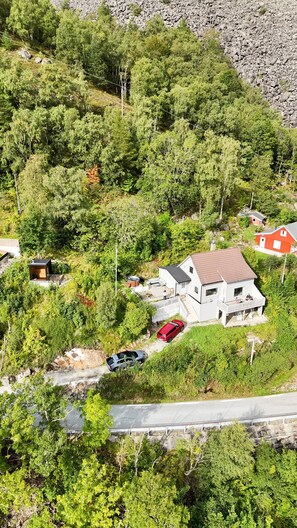 Un quartier résidentiel avec une maison blanche, une voiture rouge et un petit chalet.