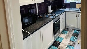A kitchen with white cabinets, a gas stove, a microwave, and a coffee maker. - Stylish 2 Bed in Manchester City Centre Fast Wi-Fi (Manchester)