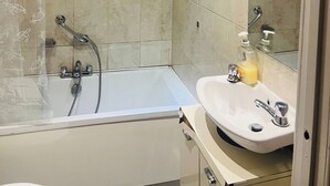 A modern bathroom with a bathtub, shower, and sink. - Stylish 2 Bed in Manchester City Centre Fast Wi-Fi (Manchester)