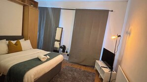 A hotel room with a bed, a desk, a television, and a large window. - Stylish 2 Bed in Manchester City Centre Fast Wi-Fi (Manchester)