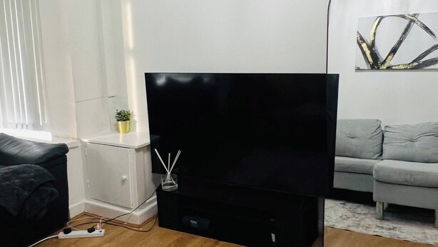 A modern living room with a flat-screen TV, a grey sofa, a coffee table, and a floor lamp. - Stylish 2 Bed in Manchester City Centre Fast Wi-Fi (Manchester)