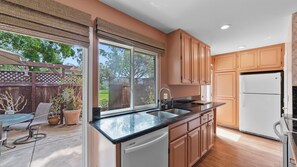 A kitchen with a large window, wooden cabinets, a sink, and a refrigerator. - Sea Bird & Pool Near the Beach and Track (Solana Beach)