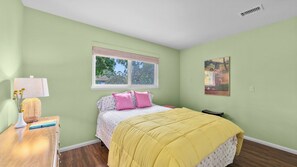 A bedroom with a bed, a window, a bedside table with a lamp, and a painting on the wall. - Sea Bird & Pool Near the Beach and Track (Solana Beach)