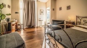 Ein Hotelzimmer mit einem Bett, einem Schreibtisch mit Stuhl, einer Zimmerpflanze und Blick ins Freie durch ein Fenster.