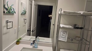 Et stilfuldt badeværelse med et stort spejl, vask, toilet og bruseområde.