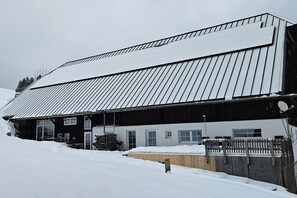 Ein Gebäude mit einem geneigten Dach, einem Holzzaun und einem mit Schnee bedeckten Boden.