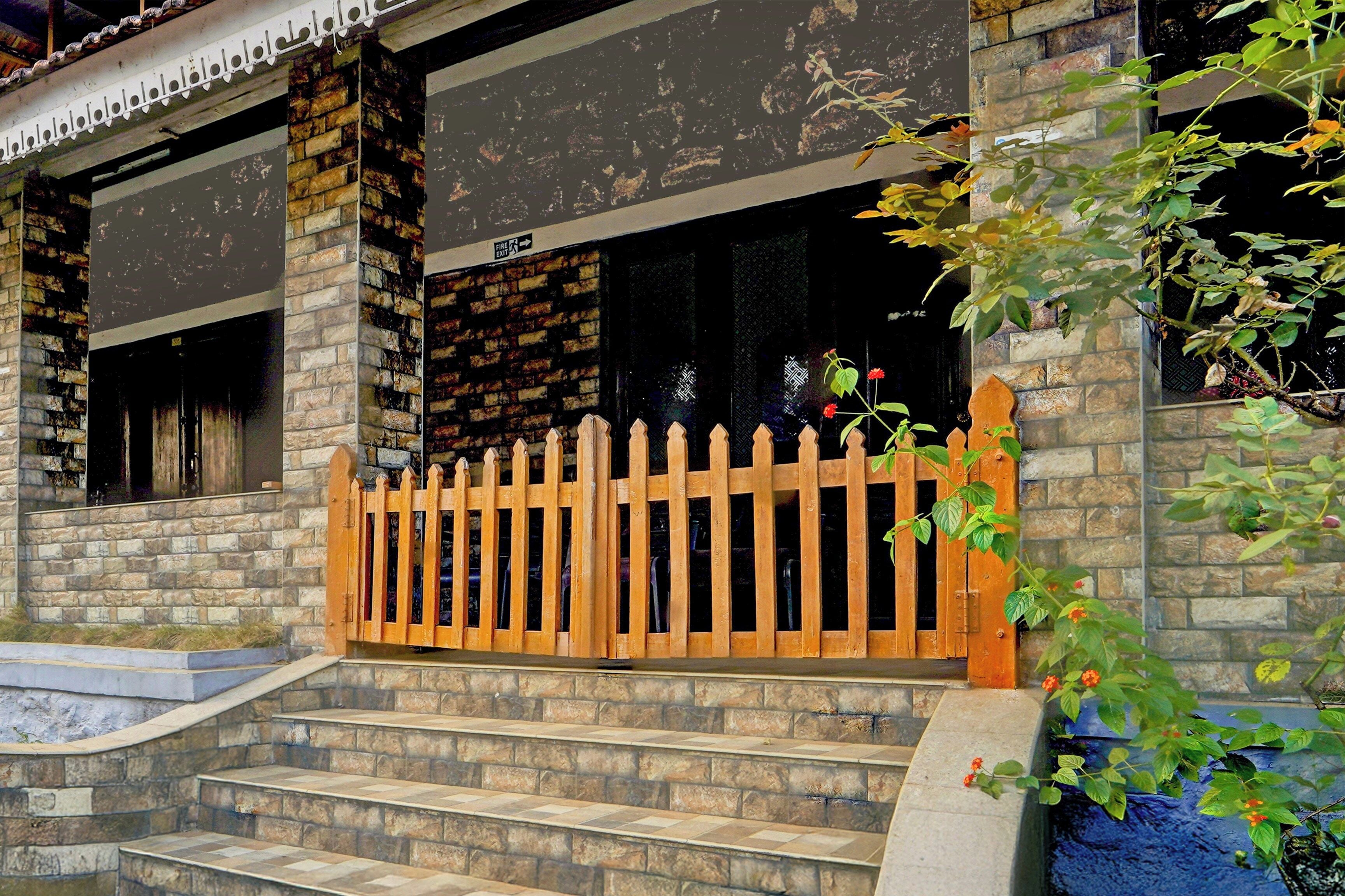 A stone building with a wooden fence and steps leading to a door.
