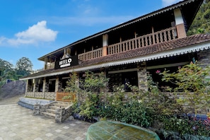 A hotel with a traditional architectural style, featuring a balcony with a decorative railing, a stone facade, and a sign indicating it is a company-serviced hotel.