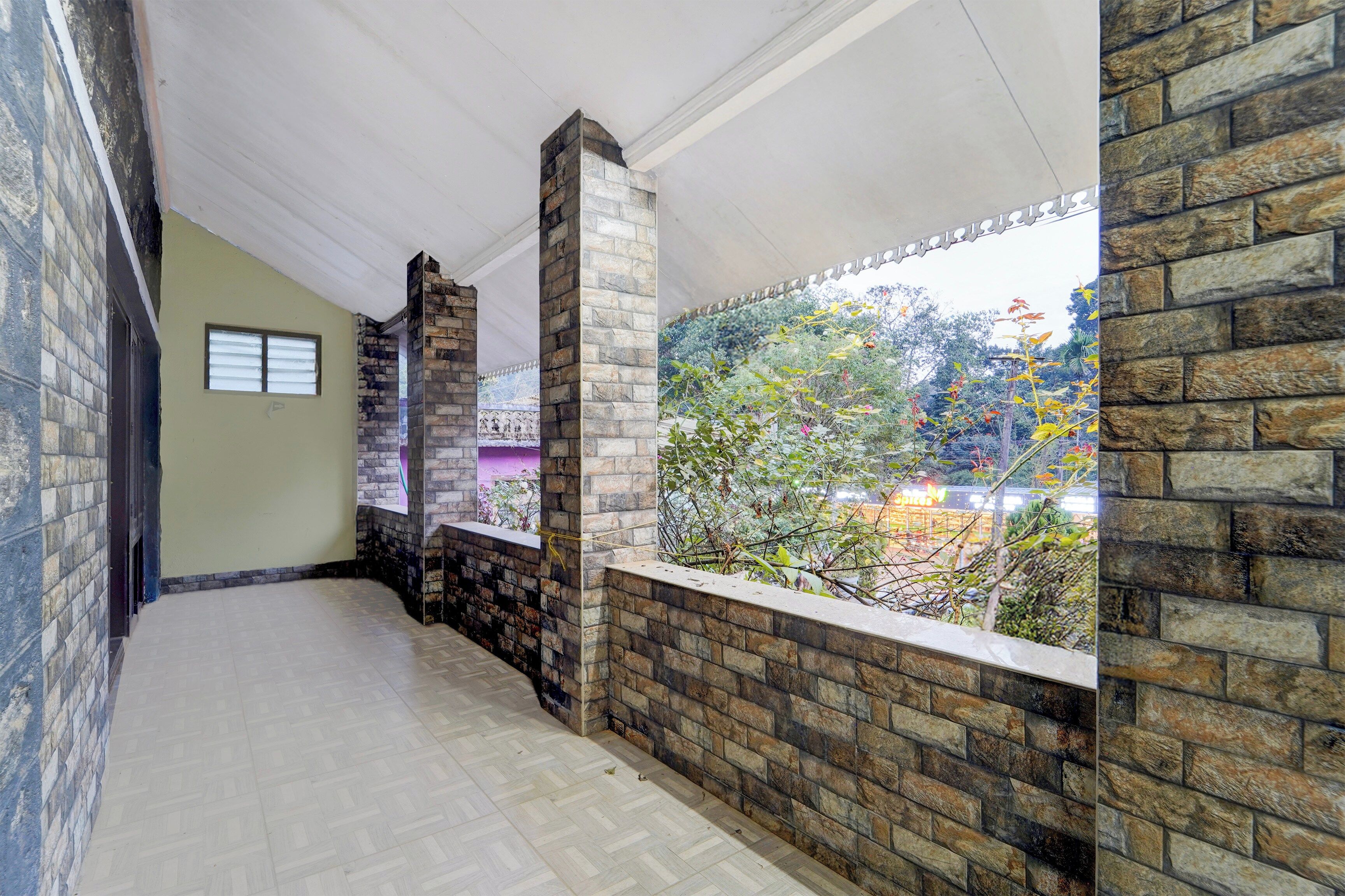 A corridor with stone walls, a window overlooking greenery, and a tiled floor.