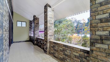 A corridor with stone walls, a window overlooking greenery, and a tiled floor.