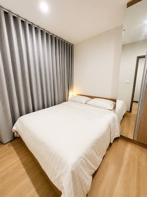 Ett hotellrum med en stor säng, ett trägolv och en spegel på en av väggarna.