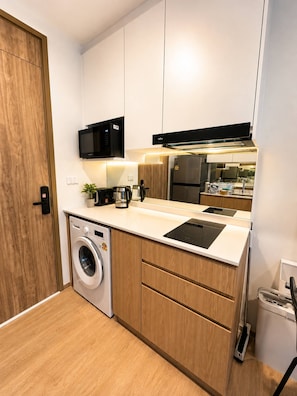Cocina compacta equipada con lavadora, microondas, estufa y refrigerador.