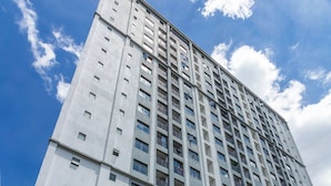 Un immeuble de grande hauteur doté de nombreux balcons et d’une entrée sécurisée par un portail.