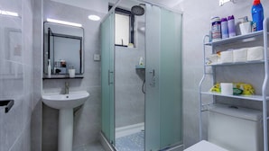 Une salle de bain moderne avec une douche à parois de verre, un lavabo sur colonne et des toilettes.