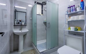 Ein modernes Badezimmer mit einer Glaskabine zur Dusche, einem Standwaschbecken und einer Toilette.
