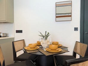 Uma sala de jantar com mesa redonda, quatro cadeiras e um objeto decorativo no centro.