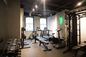 Ein Fitnessstudio mit Laufbändern, Kurzhanteln und Krafttrainingsgeräten.