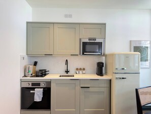 Eine kleine Küche mit Mikrowelle, Herd, Spüle und Kühlschrank.