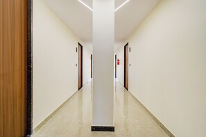A long, narrow hallway with doors on both sides, a polished floor, and a fire extinguisher mounted on the wall. - Townhouse OAK Owaisi Hospital (Hyderabad)
