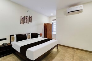A hotel room with a bed, a nightstand, a phone, a window, and an air conditioning unit.