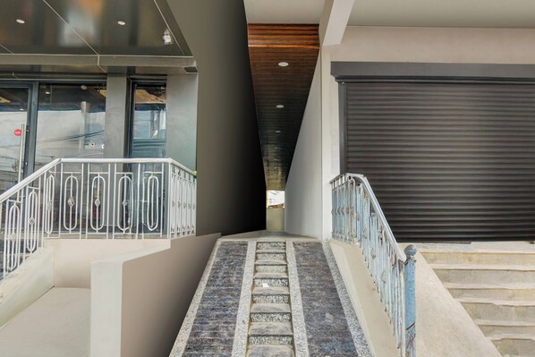 A staircase leading to a building entrance with a metal railing and a closed garage door.