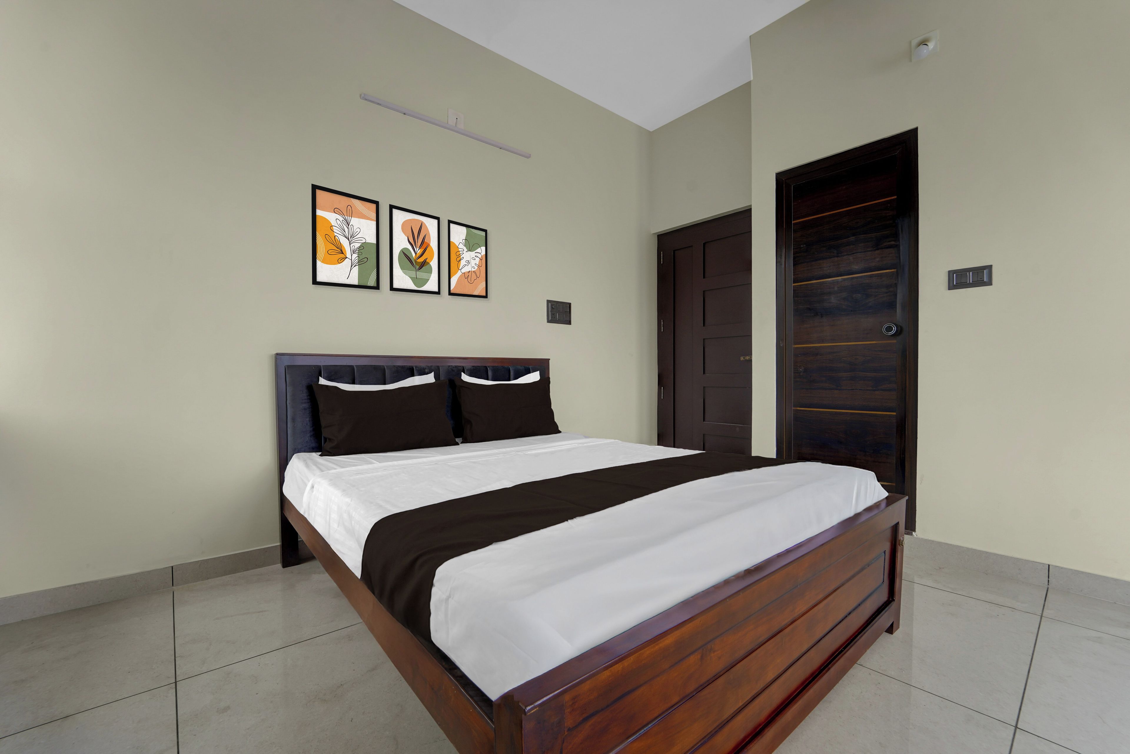 Un dormitorio con una cama, una puerta y tres cuadros en la pared.