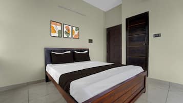 Un dormitorio con una cama, una puerta y tres cuadros en la pared.