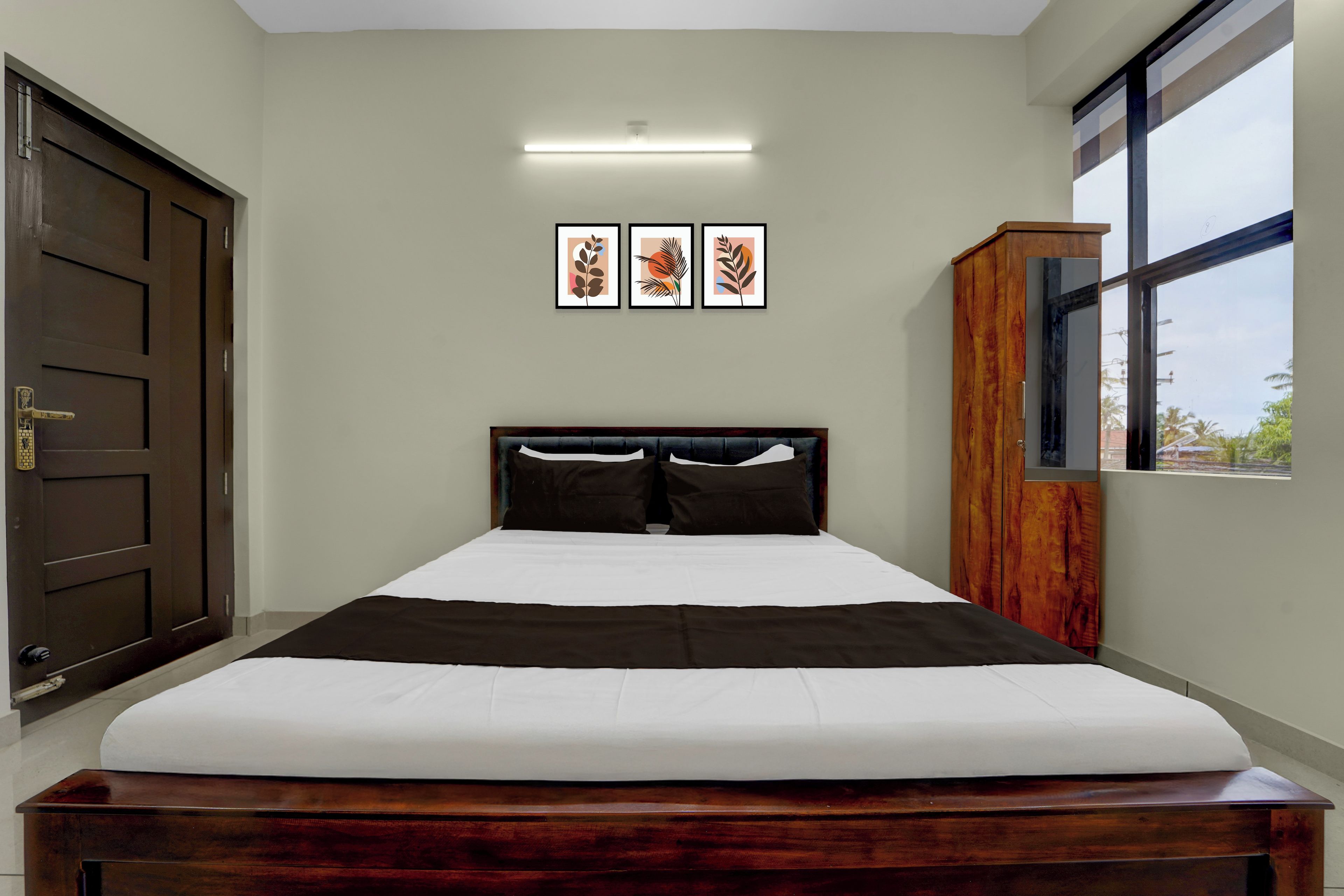A bedroom with a bed, a wardrobe, a door, and framed artwork on the wall.