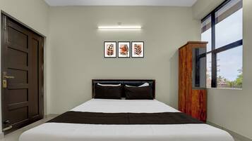 A bedroom with a bed, a wardrobe, a door, and framed artwork on the wall.