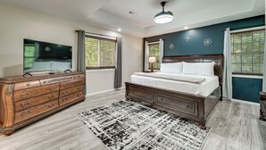 Ein Schlafzimmer mit einem Holzkapfen, einem Bett mit weißer Bettdecke, einem gemusterten Teppich und einem Deckenventilator.