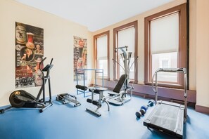 Ein Fitnessstudio mit Trainingsgeräten, Postern an der Wand und großen Fenstern.