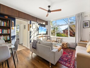 A modern living room with a sofa, armchairs, a dining table, and a bookshelf. - Peaceful Hideaway 2-bed Apartment Mosman (Sydney)