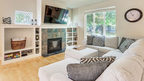 Una sala de estar con chimenea, televisor y sofá con cojines estampados.