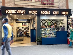 A bar and cafe with a signboard listing amenities like scenic views, music, rooms, cafe, and food.