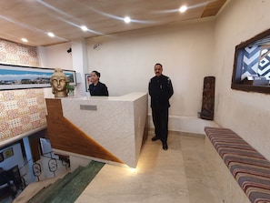 A reception desk with a marble top, a Buddha statue, and a patterned wall. - Hotel Diplomat (Shimla)