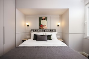 A bedroom with a bed, two bedside tables, a wall-mounted artwork, and two wall sconces. - Nouar Residence I + Breakfast - ATH Center by etouri (Athens)