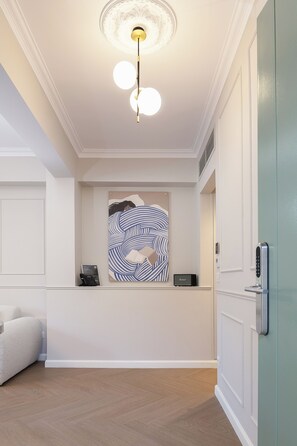 Eine Hotelhalle mit einer Rezeption, einer modernen Deckenleuchte und einem an der Wand befestigten Kunstwerk.