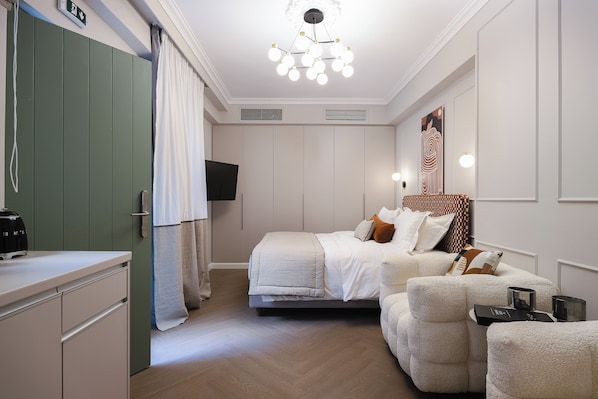 Et hotelværelse med seng, sofa, TV og minibar.