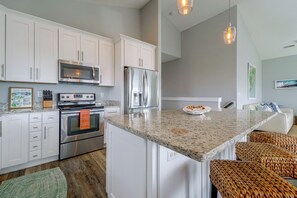 A modern kitchen with white cabinetry, stainless steel appliances, and a granite countertop. - Sunset Views + Hot Tub Soaks: Topsail Beach Gem (Surf City)