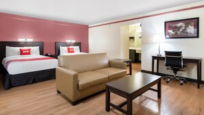 Quarto de hotel com duas camas, um sofá, uma mesa e uma cadeira.