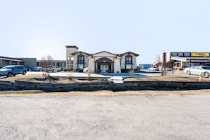 A building with a central entrance, parking lot, and a Denny's restaurant in the background. - King Bed Non Smoking (Tulsa)