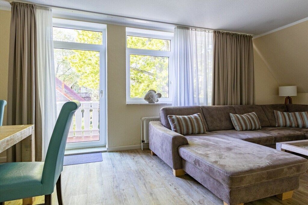 A living room with a sofa set, a chair, a table, and a window with curtains.