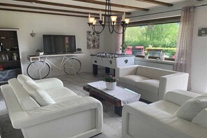 A living room with a sofa set, a foosball table, a television, and a bicycle. - by the lake with views of the lake and the Bavarian Forest, ground floor (Arrach\/ Kummersdorf)