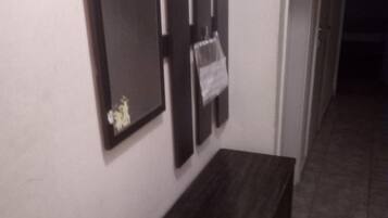 Un pasillo con un banco de madera oscura, un espejo en la pared y un pequeño cuadro enmarcado.