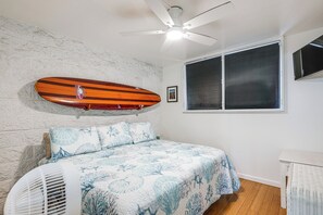 Ein Schlafzimmer mit einem Bett, einem Deckenventilator, einem Surfbrett und einem Fenster.