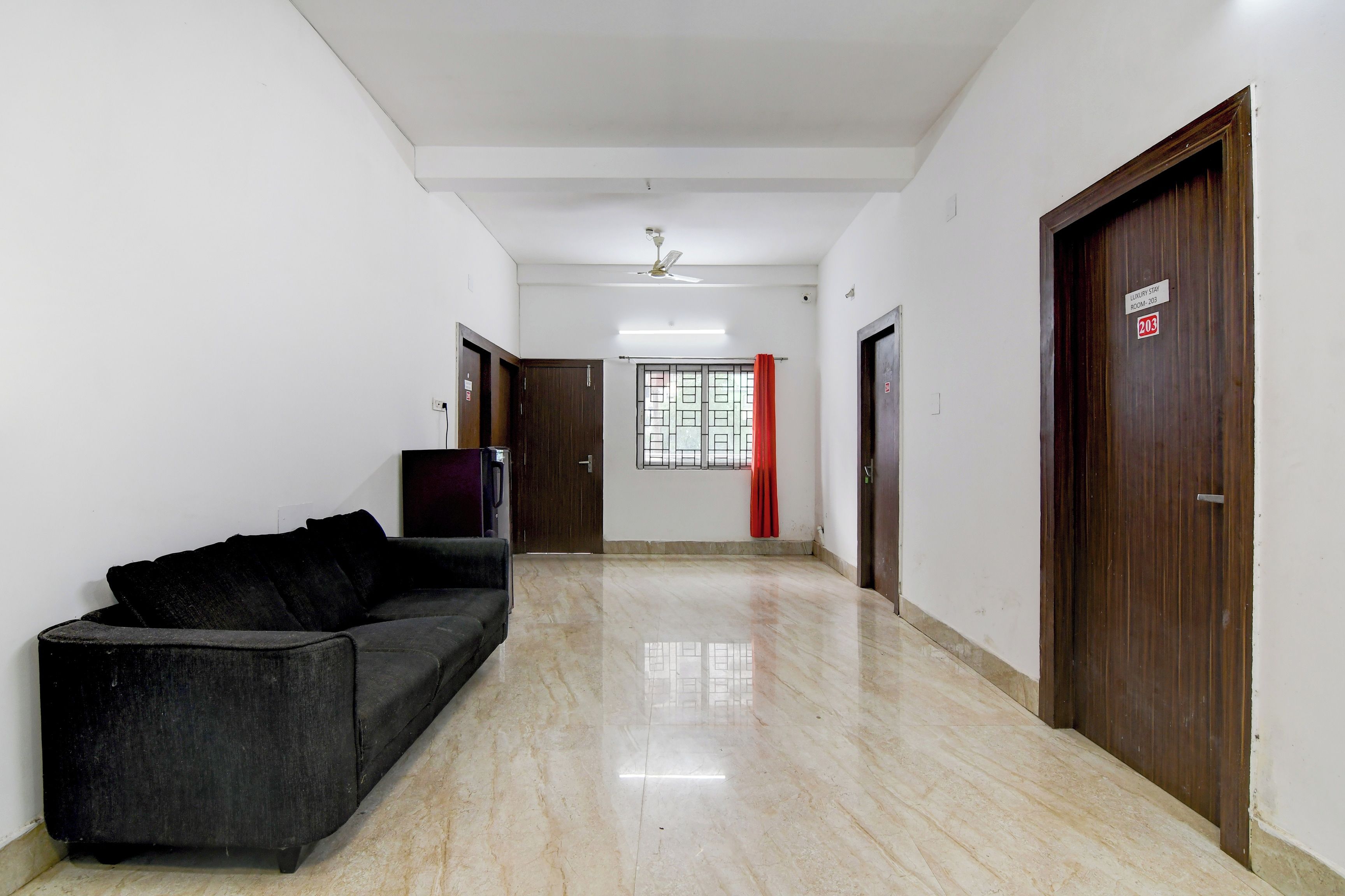 A corridor with a sofa, a ceiling fan, and doors leading to rooms.