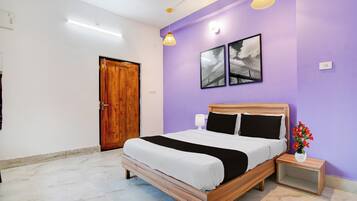 A bedroom with a wooden bed, a nightstand, a wall-mounted lamp, and a framed picture.